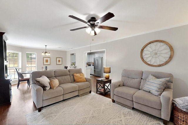 living area with wood finished floors, a ceiling fan, a chandelier, and ornamental molding