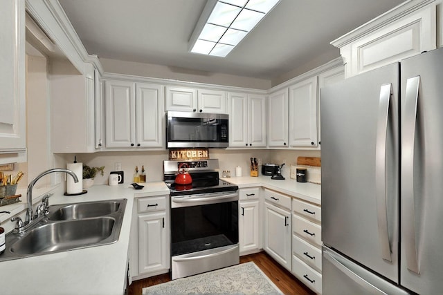 kitchen with stainless steel appliances, a sink, and white cabinetry