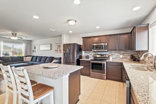 240 Willow Creek Ln, Terrell, TX 75160 - kitchen with appliances with stainless steel finishes, a sink, dark brown cabinets, light tile patterned flooring, and decorative backsplash