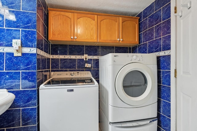 7600 Independence Dr, The Colony, TX 75056 - laundry area featuring tile walls, washer and clothes dryer, and a textured ceiling