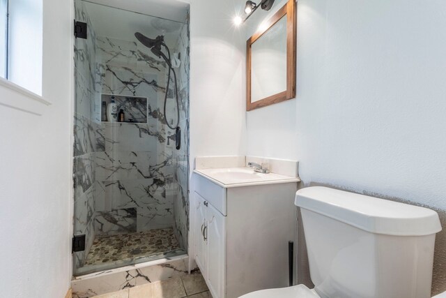 bathroom with a marble finish shower, toilet, and vanity