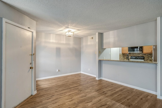 12480 Abrams Rd Unit 2801, Dallas, TX 75243 - unfurnished living room featuring wood finished floors, a textured ceiling, and baseboards