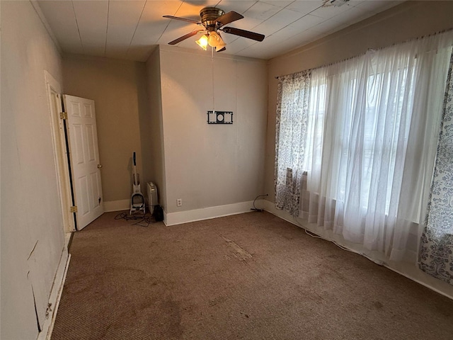 carpeted spare room with a ceiling fan and baseboards