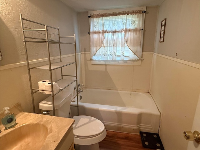 bathroom featuring toilet, wood finished floors, a textured wall, and vanity