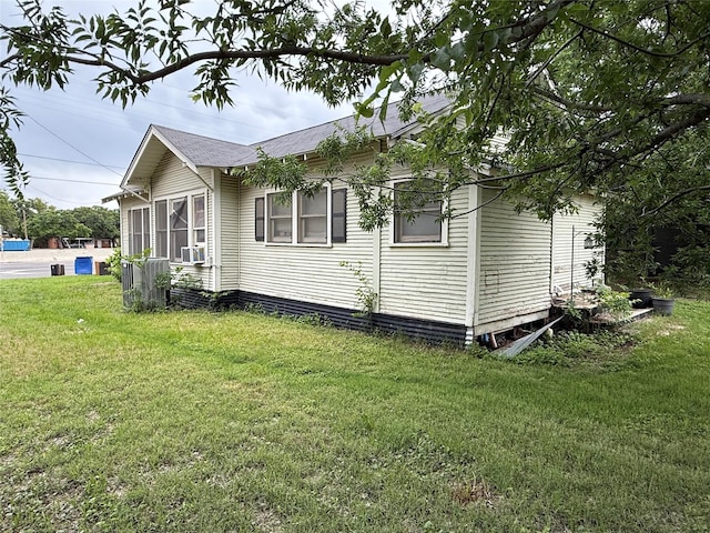 view of side of property featuring a lawn, a shingled roof, and cooling unit