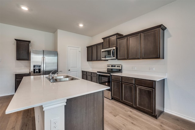 13156 Sanctuary Dr, Providence Village, TX 76227 - kitchen featuring appliances with stainless steel finishes, a sink, light wood-style floors, dark brown cabinetry, and recessed lighting