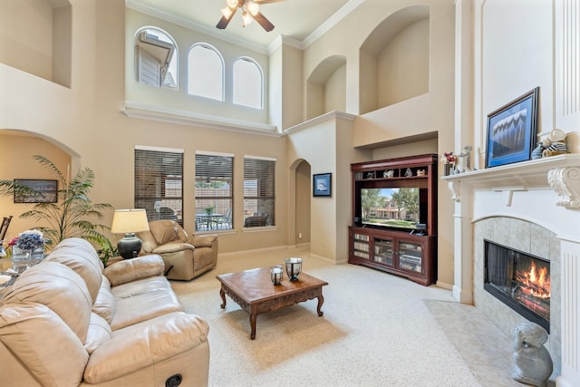 3455 Crosshaven Ln, Frisco, TX 75033 - carpeted living area featuring ornamental molding, ceiling fan, a tiled fireplace, a towering ceiling, and baseboards