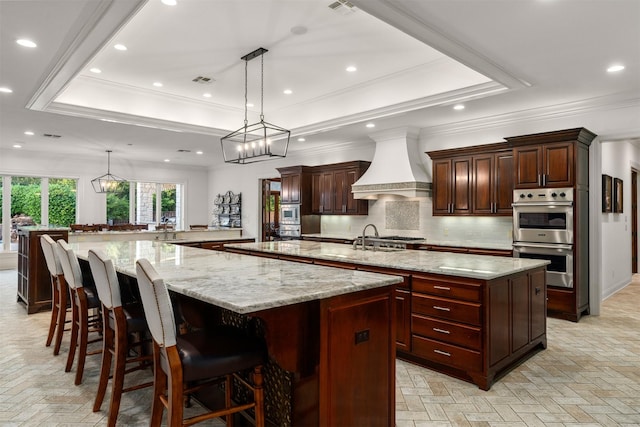 1020 Canyon Trl, Waco, TX 76657 - kitchen with a spacious island, custom range hood, stainless steel double oven, a tray ceiling, and decorative backsplash