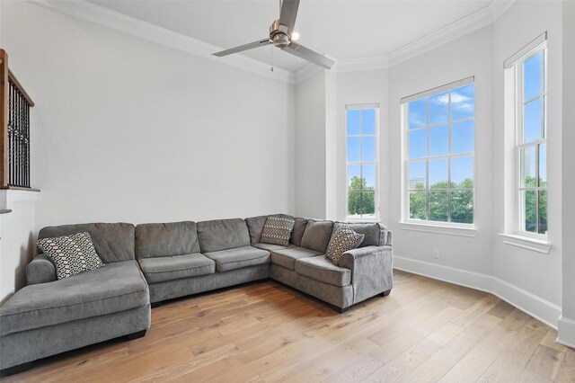 living area with ornamental molding, light wood-style floors, ceiling fan, and baseboards