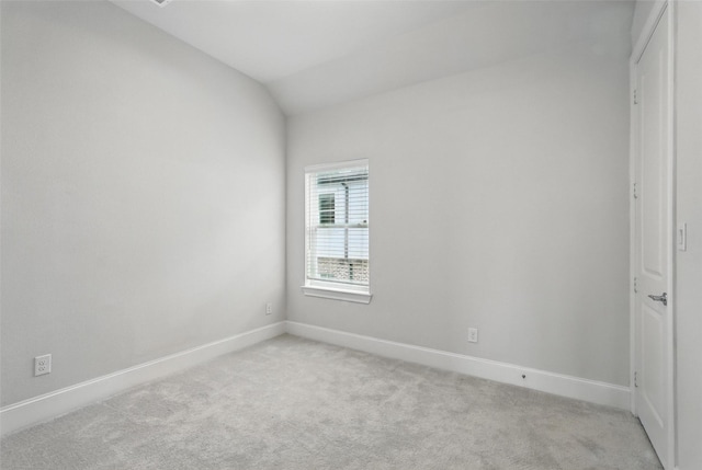 empty room featuring light colored carpet, baseboards, and vaulted ceiling