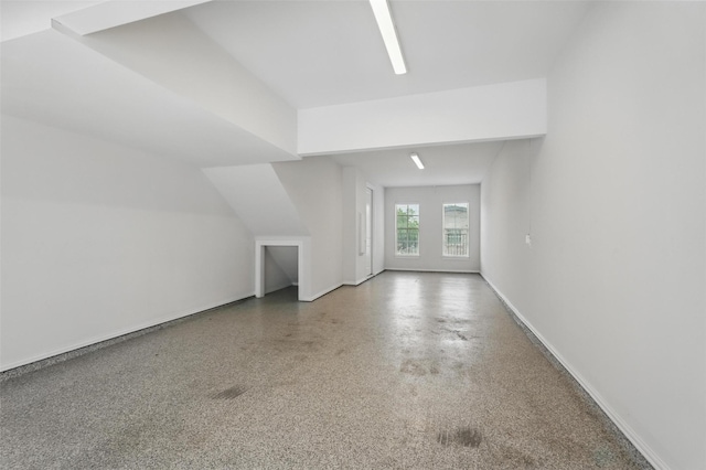 bonus room with baseboards and speckle patterned floor