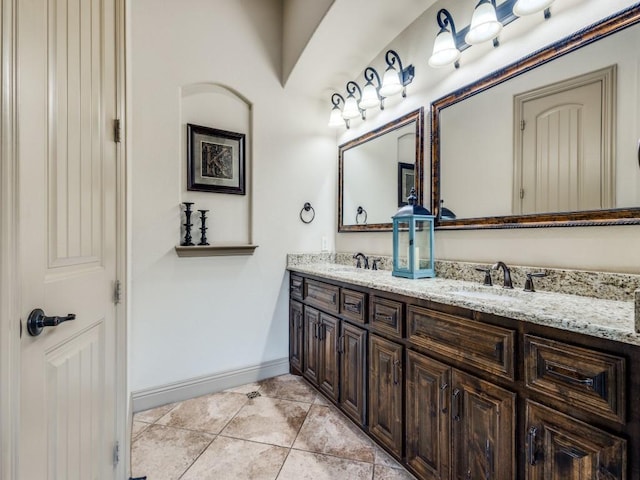bathroom with double vanity, baseboards, and tile patterned flooring