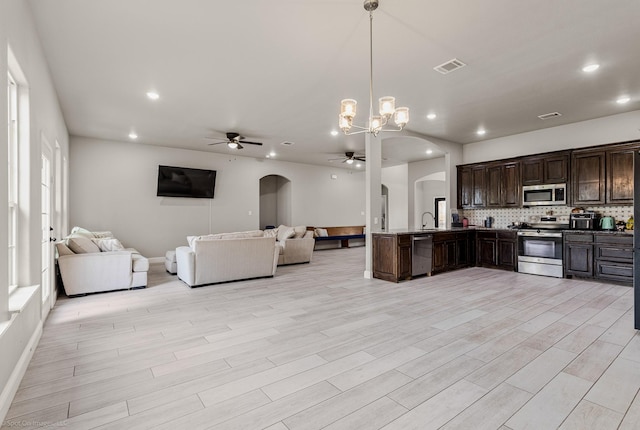 5585 Justine Pl, Fort Worth, TX 76126 - kitchen featuring appliances with stainless steel finishes, arched walkways, ceiling fan, open floor plan, and tasteful backsplash