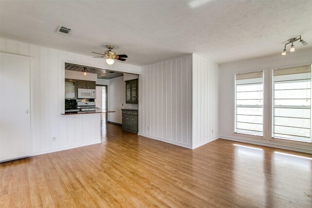 214 S Clark St, Rockwall, TX 75087 - unfurnished living room featuring light wood-type flooring, ceiling fan, baseboards, and a textured ceiling