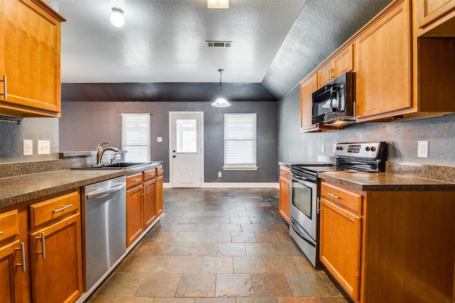110 Commonwealth Cir, Waxahachie, TX 75165 - kitchen featuring stainless steel appliances, a sink, stone tile flooring, a textured ceiling, and vaulted ceiling