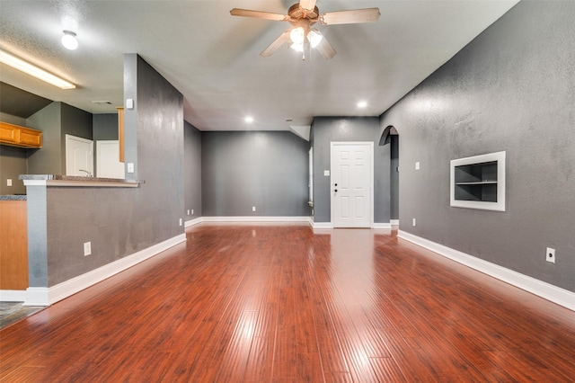 110 Commonwealth Cir, Waxahachie, TX 75165 - unfurnished living room featuring arched walkways, a ceiling fan, wood finished floors, baseboards, and recessed lighting