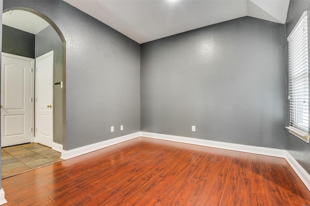 110 Commonwealth Cir, Waxahachie, TX 75165 - empty room featuring arched walkways, wood finished floors, baseboards, and a textured wall