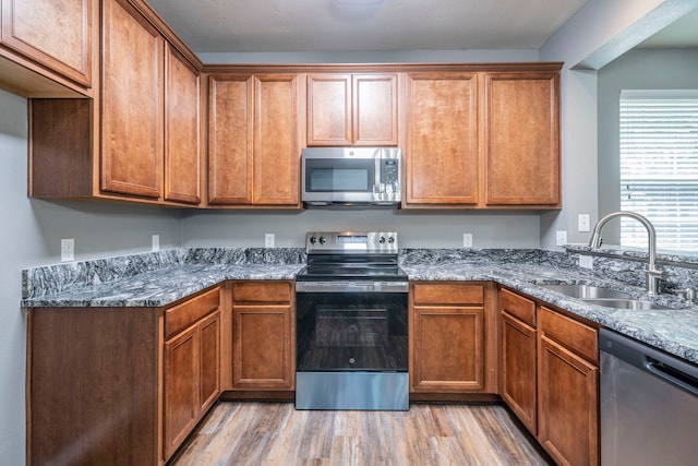 4928 Heather Glen Trl, Mckinney, TX 75070 - kitchen featuring appliances with stainless steel finishes, a sink, light wood-style flooring, and brown cabinetry