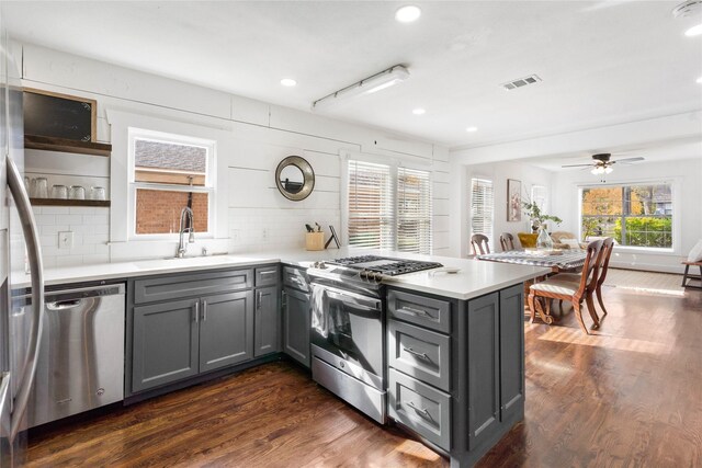 kitchen featuring stainless steel appliances, gray cabinetry, a peninsula, decorative backsplash, and recessed lighting