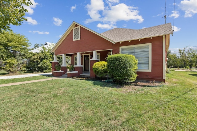 bungalow featuring a porch, a front yard, and roof with shingles