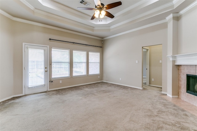 unfurnished living room with ornamental molding, carpet floors, ceiling fan, a tile fireplace, and a tray ceiling