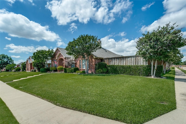 view of front of property featuring brick siding, a front lawn, and roof with shingles