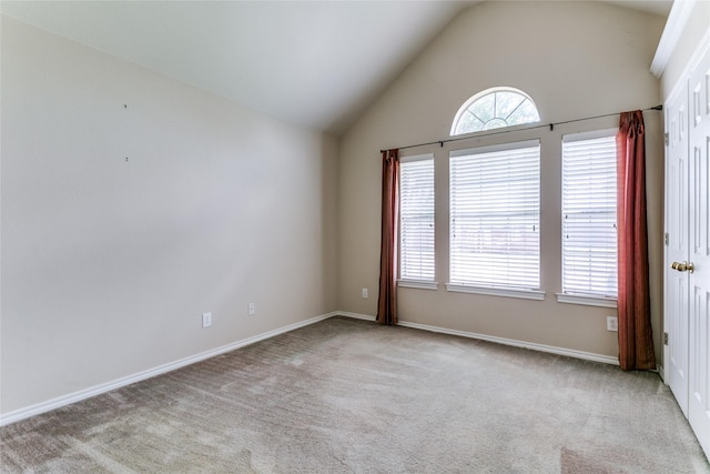 carpeted empty room with baseboards and high vaulted ceiling