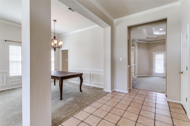 unfurnished dining area with light colored carpet, ornamental molding, light tile patterned floors, a chandelier, and a decorative wall