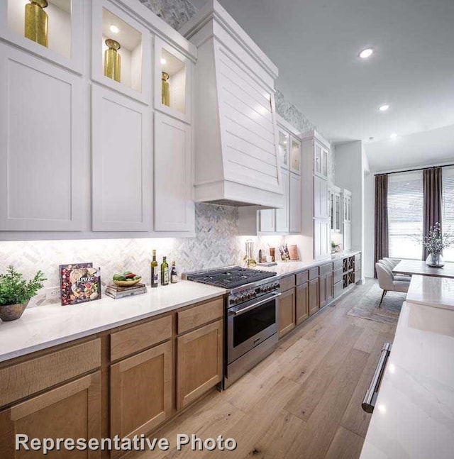 1409 Sire Ct, Aubrey, TX 76227 - kitchen featuring stainless steel stove, light wood finished floors, tasteful backsplash, custom exhaust hood, and recessed lighting