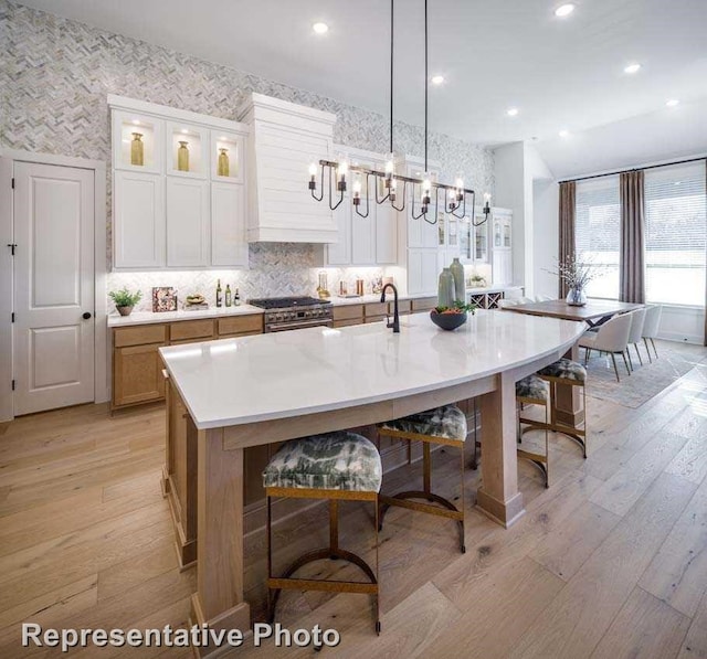 1409 Sire Ct, Aubrey, TX 76227 - kitchen with a chandelier, light wood-style floors, a spacious island, white cabinets, and a kitchen bar