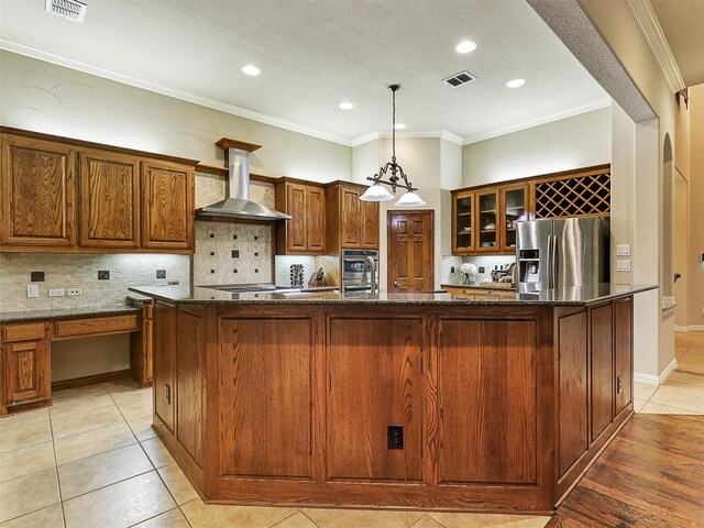 6769 Canal Ct, Grand Prairie, TX 75054 - kitchen featuring stainless steel refrigerator with ice dispenser, wall chimney range hood, a large island, decorative backsplash, and dark stone counters