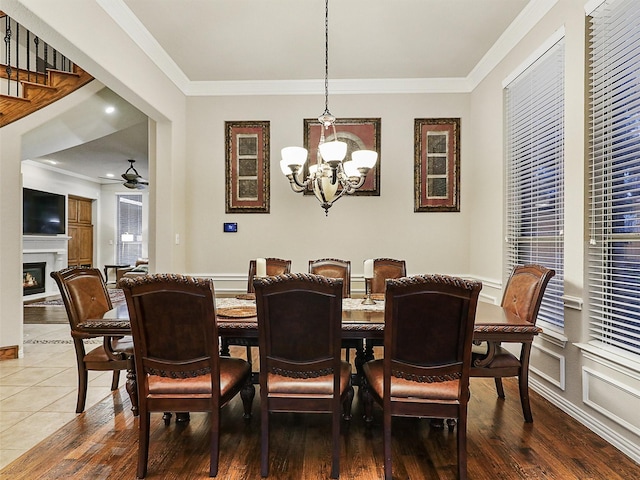 6769 Canal Ct, Grand Prairie, TX 75054 - dining area featuring a chandelier, ornamental molding, a warm lit fireplace, wood finished floors, and a ceiling fan