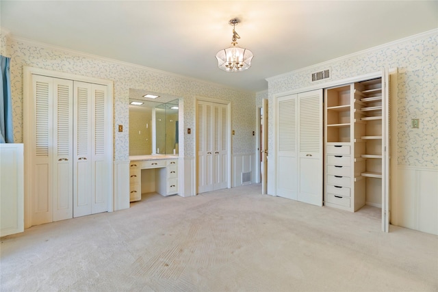 214 Country Club Rd, Hillsboro, TX 76645 - unfurnished bedroom featuring wallpapered walls, two closets, ornamental molding, a chandelier, and a wainscoted wall