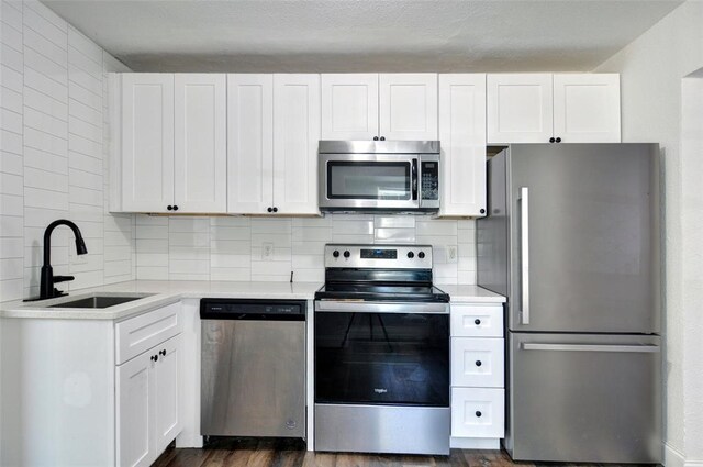 4363 Lisbon St, Fort Worth, TX 76107 - kitchen with appliances with stainless steel finishes, a sink, light countertops, backsplash, and white cabinetry