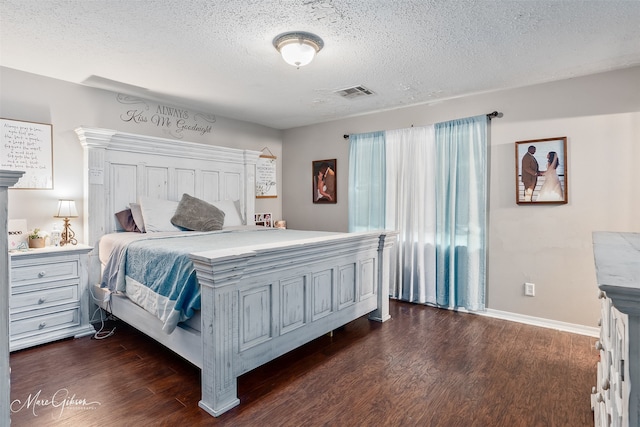 bedroom featuring dark wood-style flooring, a textured ceiling, and baseboards