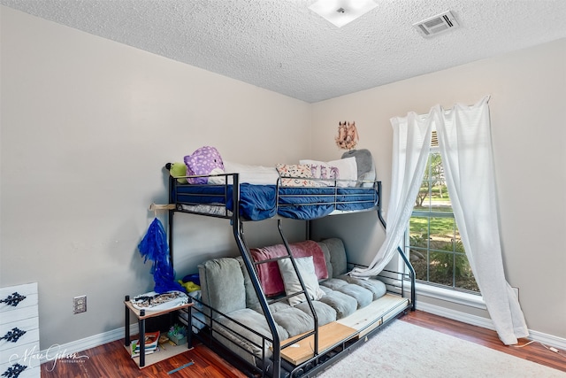 bedroom with baseboards, wood finished floors, and a textured ceiling