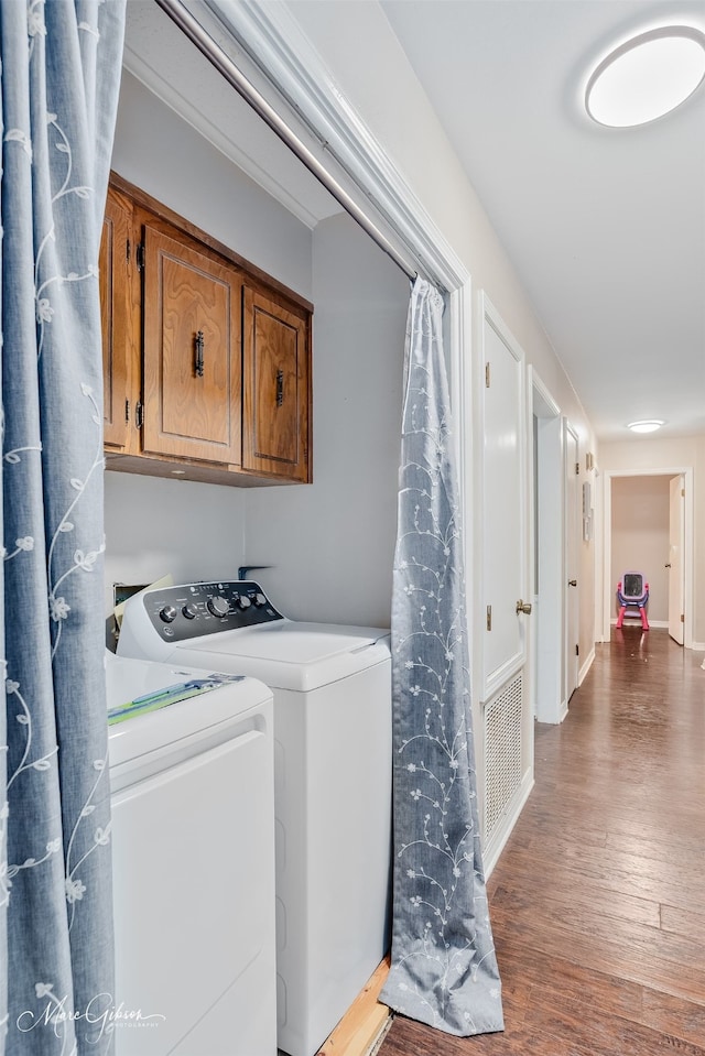 washroom featuring cabinet space, washing machine and clothes dryer, and wood finished floors