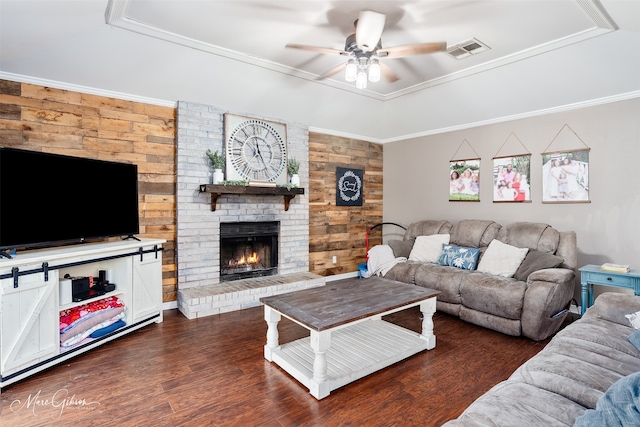 living area featuring a ceiling fan, a brick fireplace, wood finished floors, wood walls, and a raised ceiling