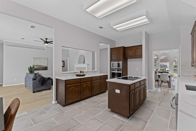 kitchen with stainless steel appliances, light countertops, ceiling fan, and a kitchen island