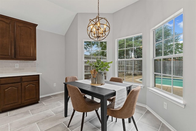 dining space with a chandelier, plenty of natural light, lofted ceiling, light tile patterned floors, and baseboards