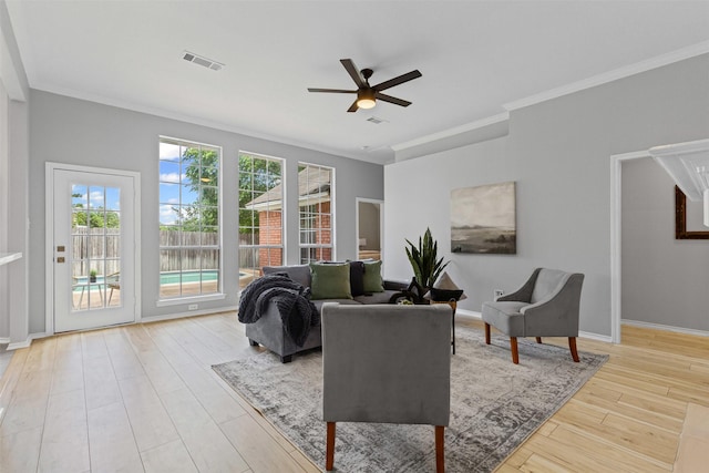 living room with a ceiling fan, ornamental molding, wood finished floors, and baseboards