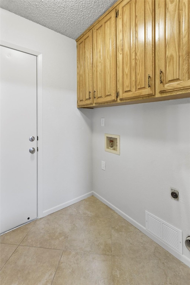 clothes washing area with cabinet space, hookup for a washing machine, hookup for an electric dryer, baseboards, and a textured ceiling