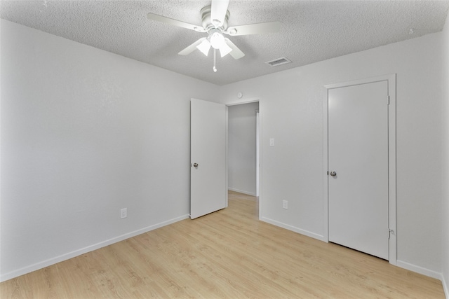 unfurnished bedroom featuring light wood-style floors, a textured ceiling, baseboards, and a ceiling fan