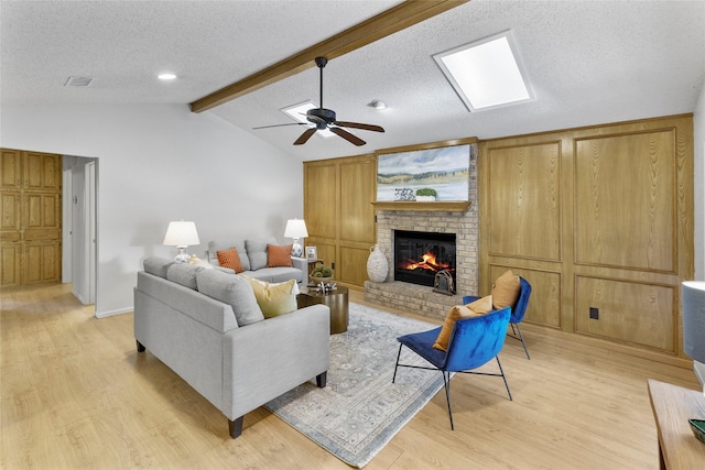 living area featuring light wood-style flooring, a fireplace, a ceiling fan, a textured ceiling, and baseboards