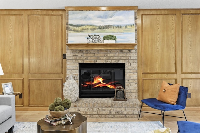 living room with a brick fireplace and wood finished floors