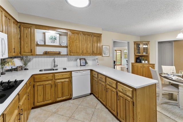 kitchen featuring white appliances, a sink, a peninsula, brown cabinetry, and a textured ceiling