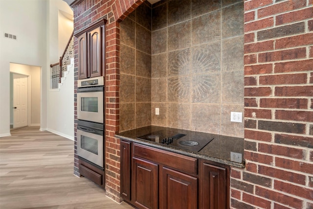 10101 Waterview Pkwy, Rowlett, TX 75089 - kitchen with black electric stovetop, stainless steel double oven, light wood finished floors, baseboards, and tasteful backsplash