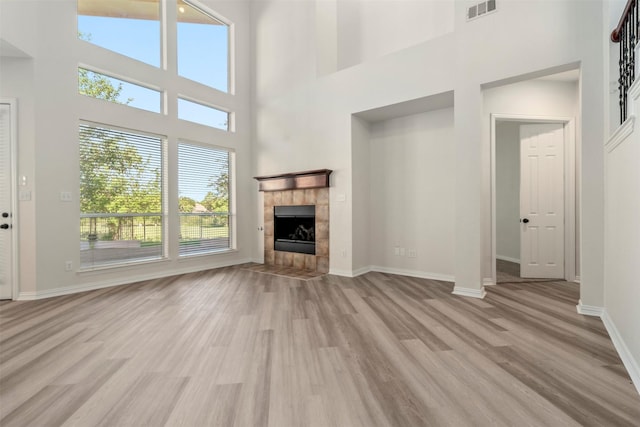 10101 Waterview Pkwy, Rowlett, TX 75089 - unfurnished living room featuring light wood-type flooring, baseboards, a towering ceiling, and a tile fireplace