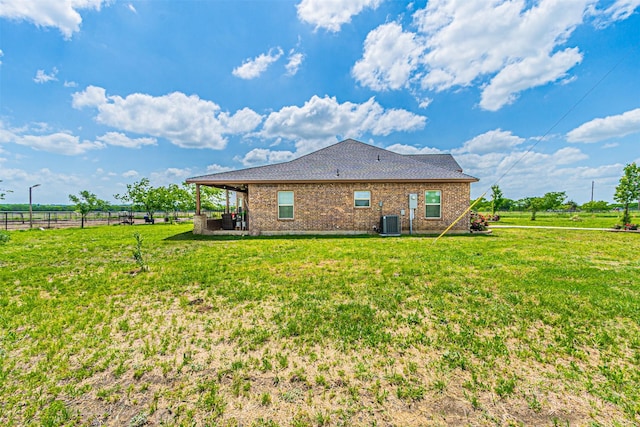 rear view of property with central AC, brick siding, and roof with shingles