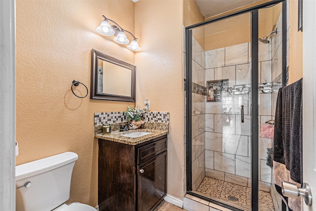 bathroom featuring a stall shower, toilet, a textured wall, vanity, and decorative backsplash